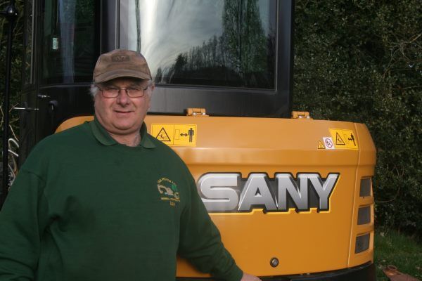 A man is standing in front of a yellow sany truck