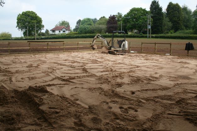 A bulldozer is moving dirt in a field with trees in the background