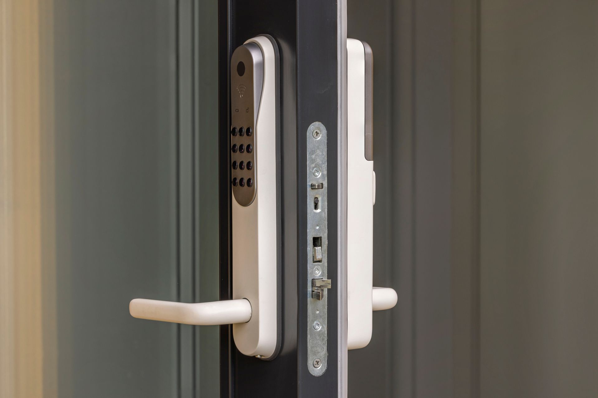 White smart door lock with keypad and handle on a gray door.