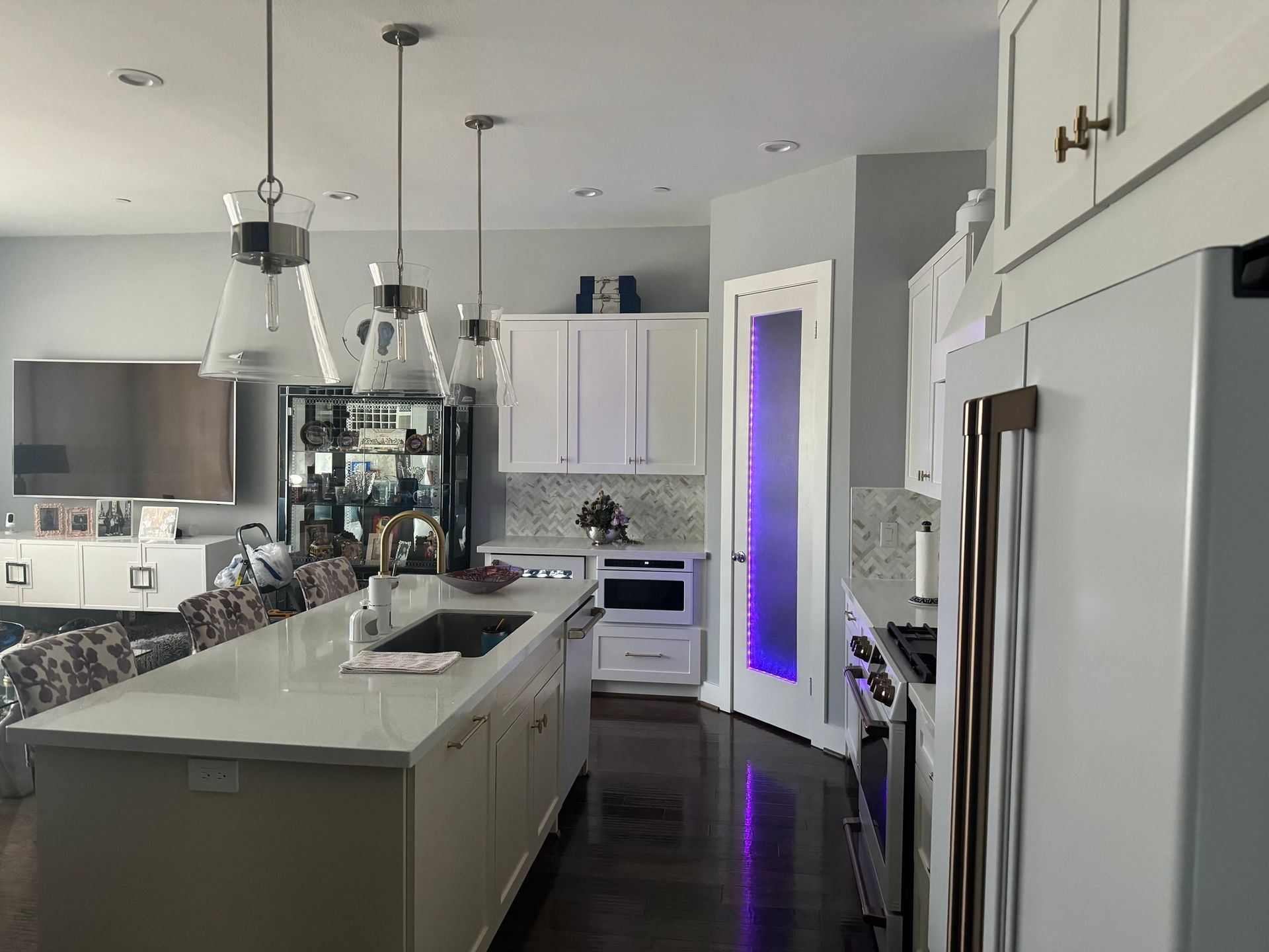Spacious kitchen with white cabinets, island, stainless steel appliances, and a dark wood floor.