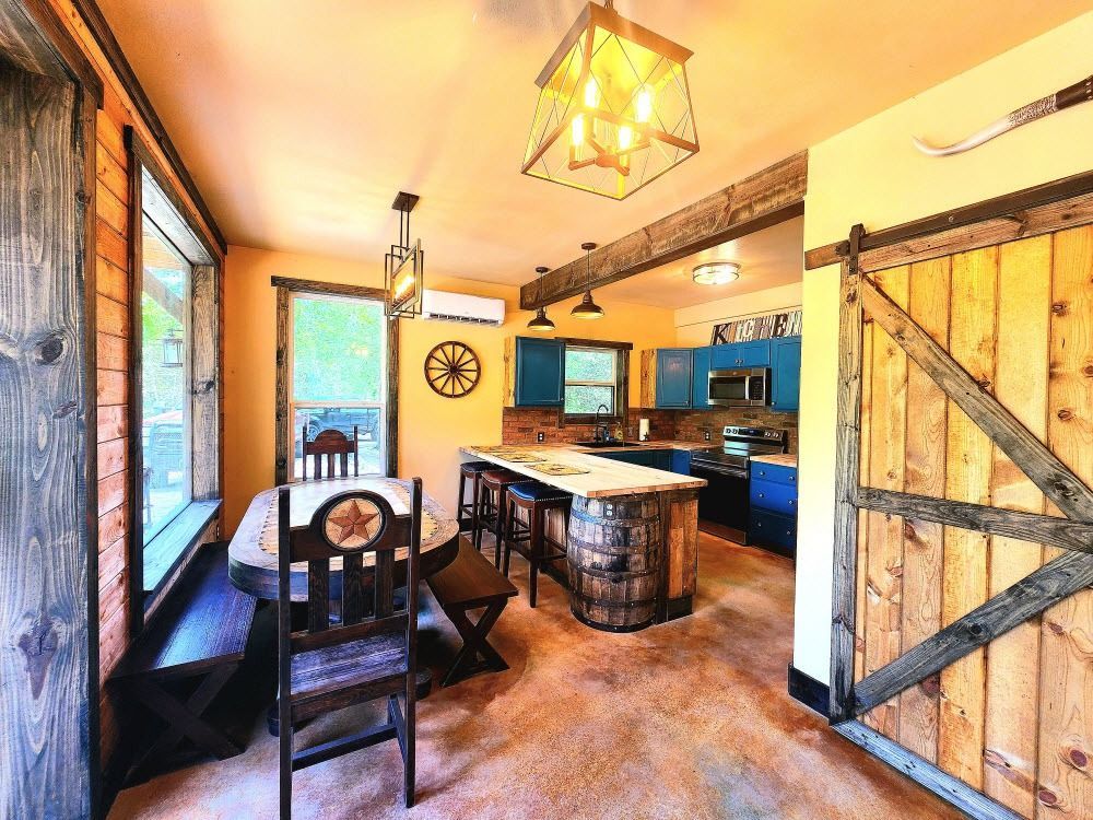 Rustic kitchen with wood accents, blue cabinets, barrel island, and barn door.