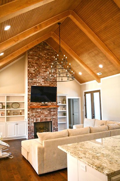 A living room with a brick fireplace and a flat screen tv.