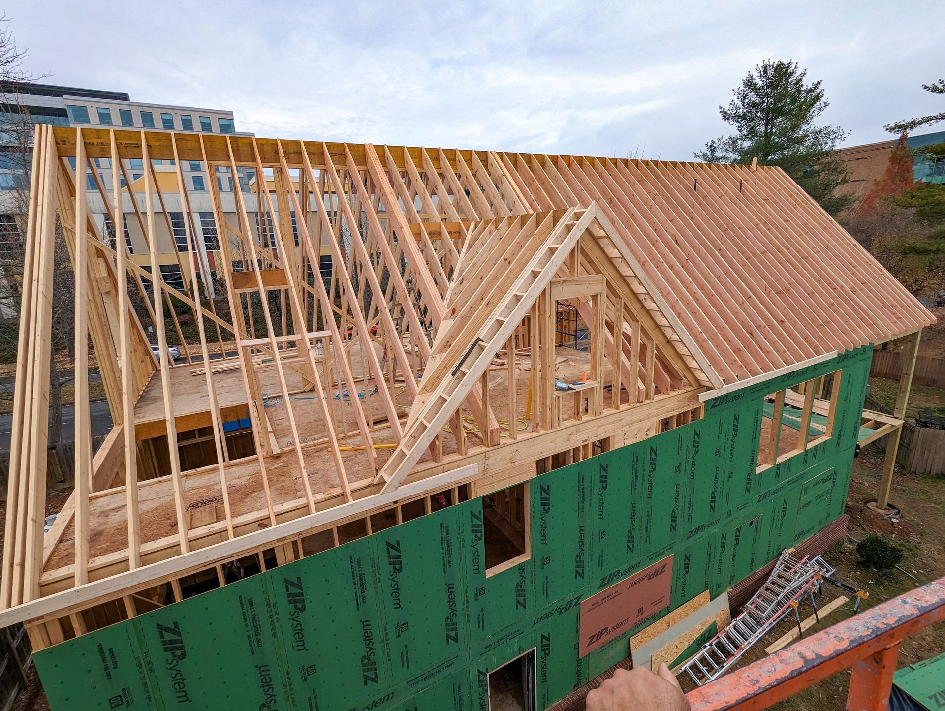 A house is being built with wooden beams and a green roof.