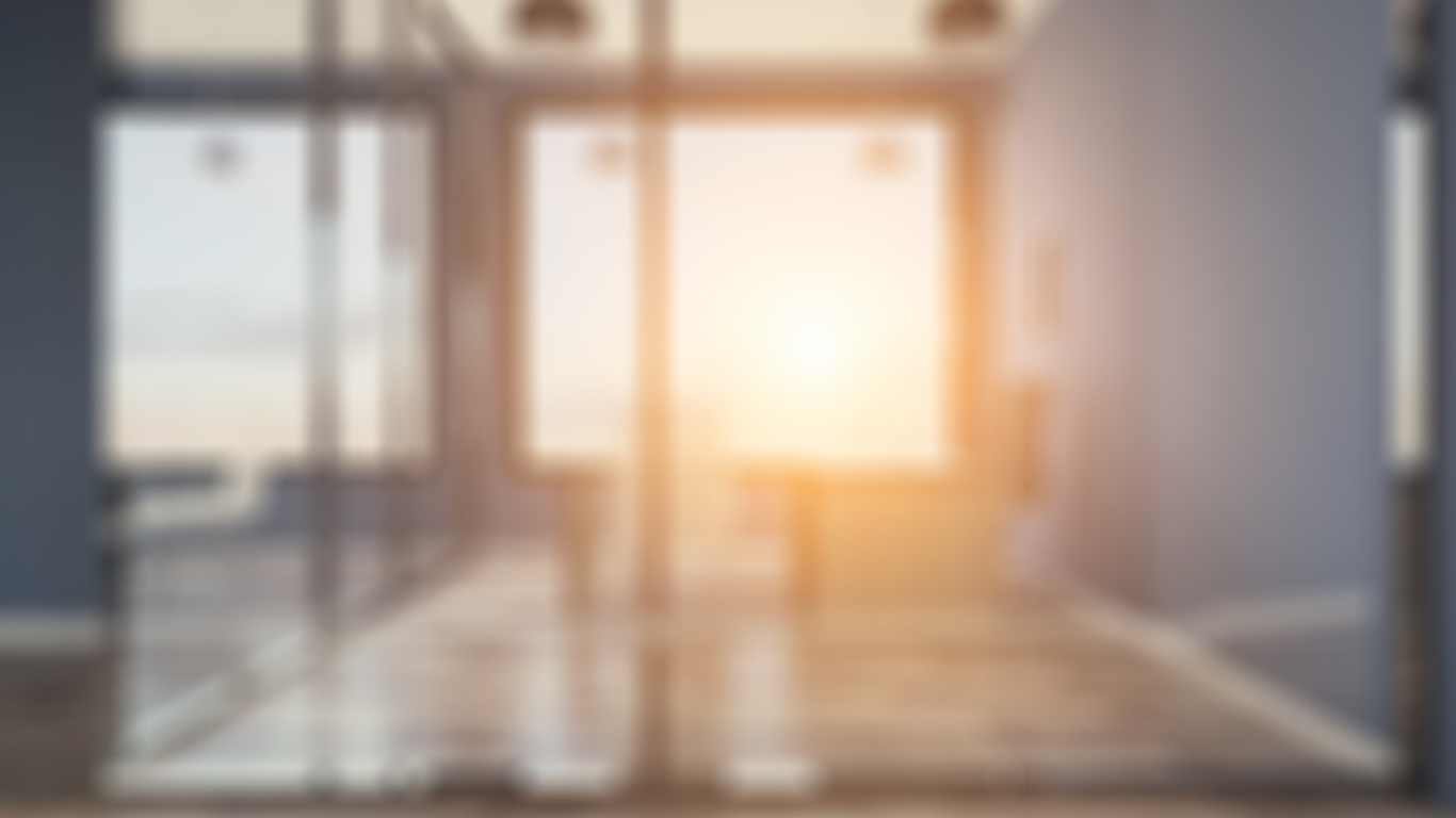 A blurry picture of a room with a lot of windows and the sun shining through them.