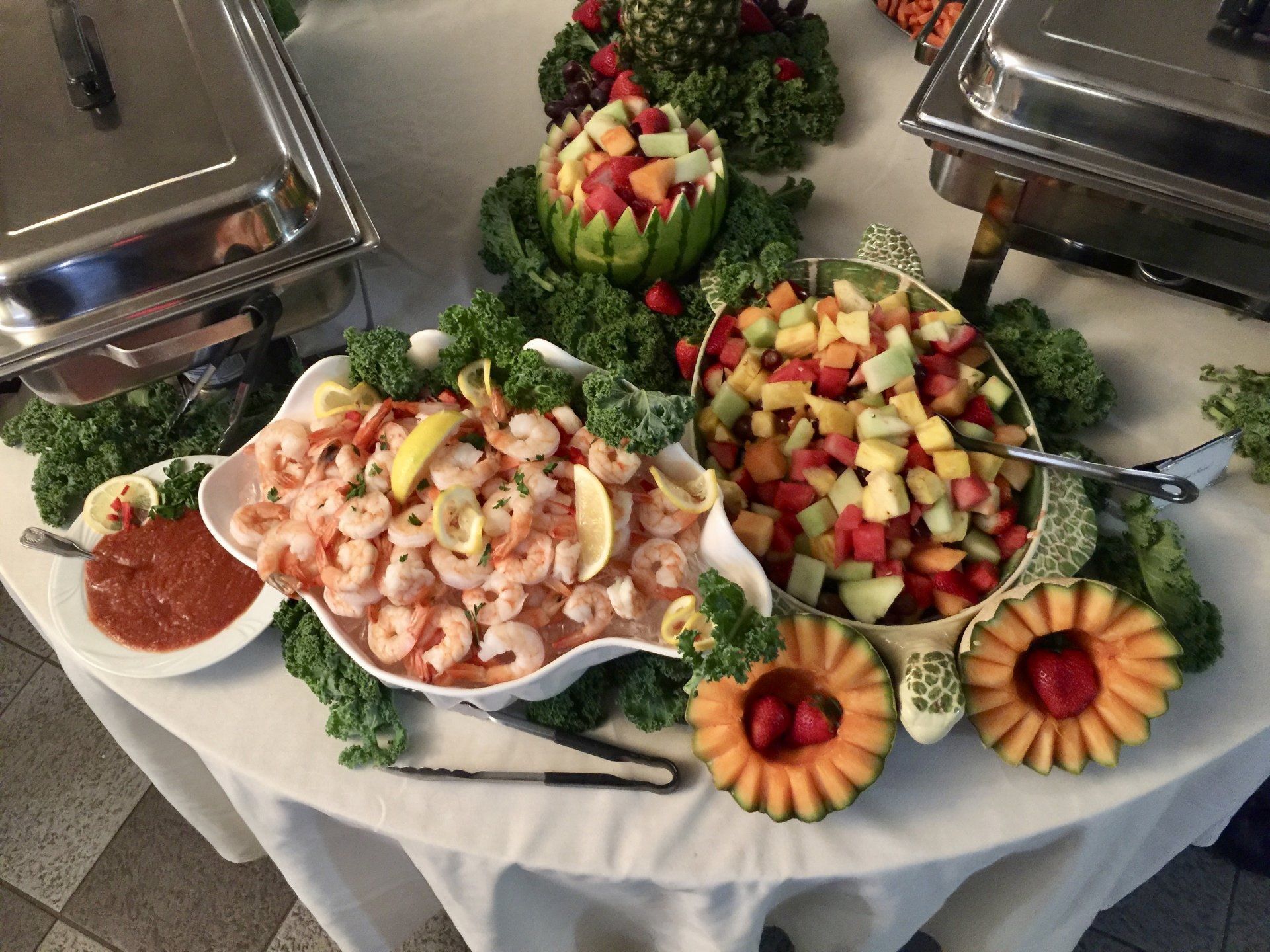 A table topped with a variety of food including shrimp and fruit.