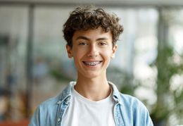 A young man with braces on his teeth is smiling for the camera.