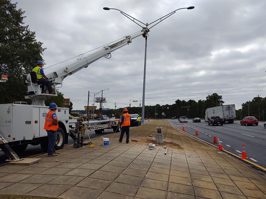 HVAC technician servicing an air conditioner outside, using tools and a pink refrigerant tank.
