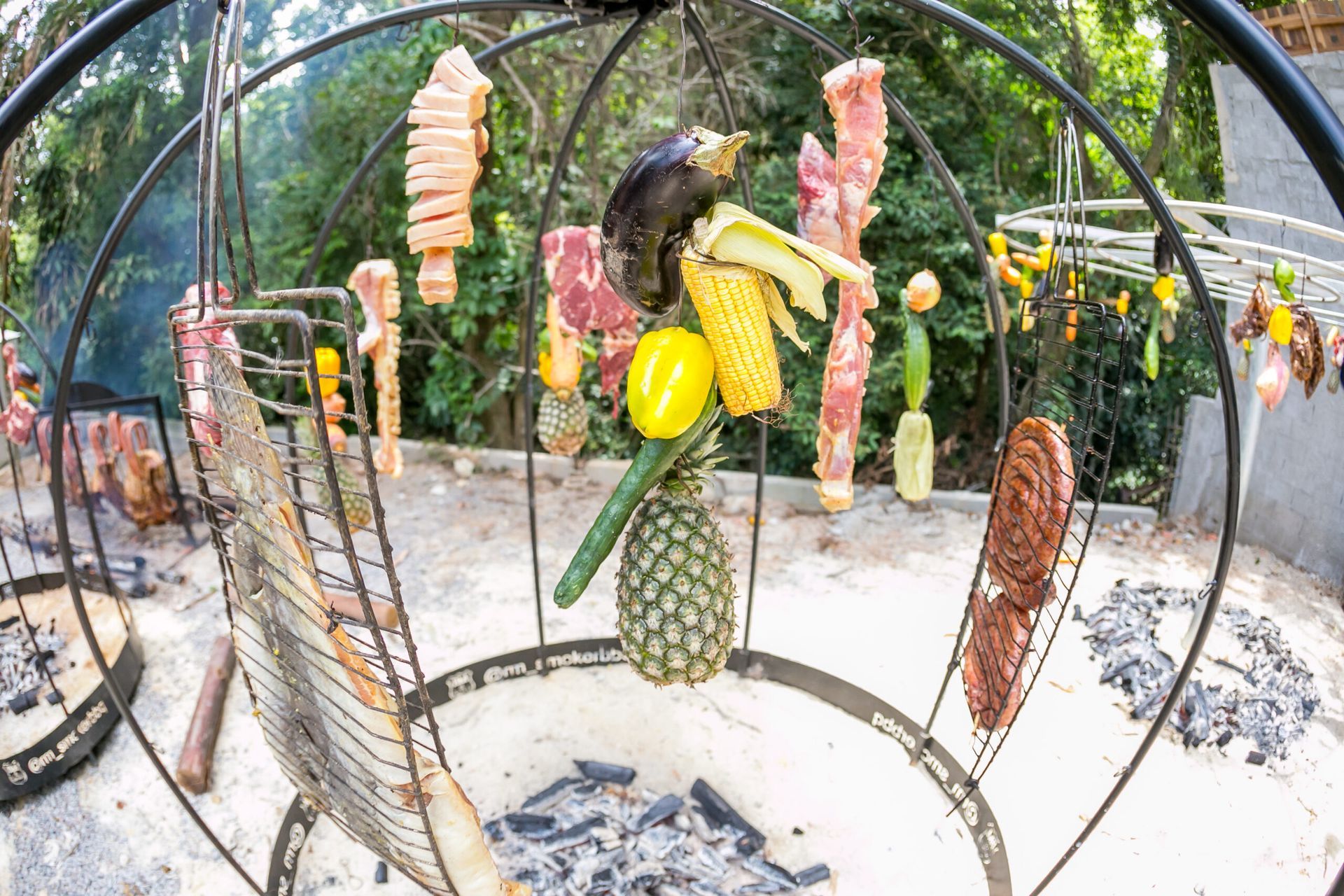 Uma grelha com carne e vegetais pendurados.