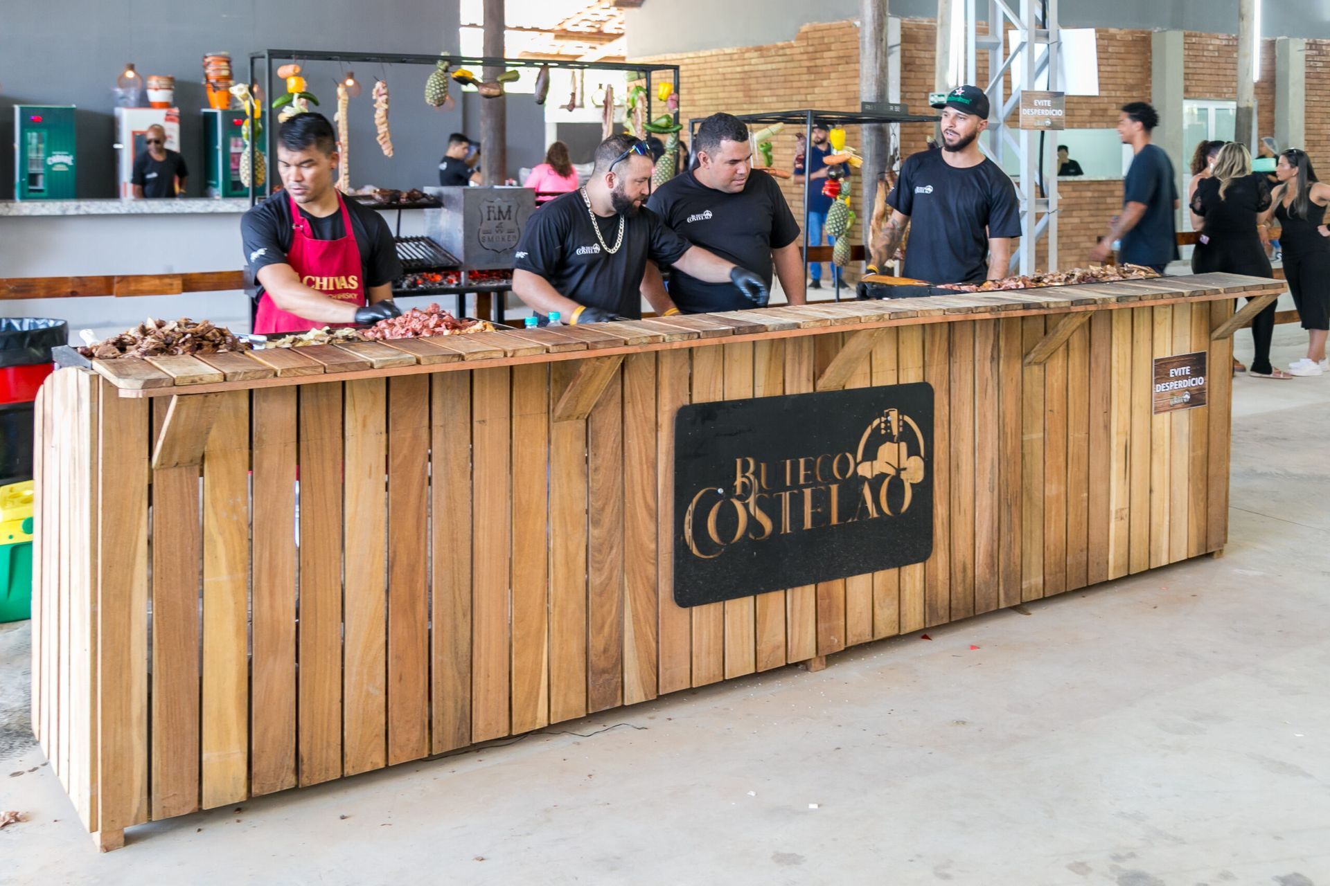 Um grupo de pessoas está em pé ao redor de um balcão de madeira.