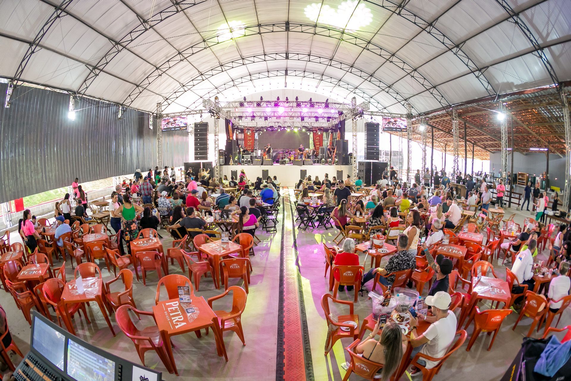 Uma grande sala cheia de mesas e cadeiras e um palco.