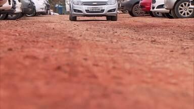 Uma fileira de carros está estacionada em uma estrada de terra.