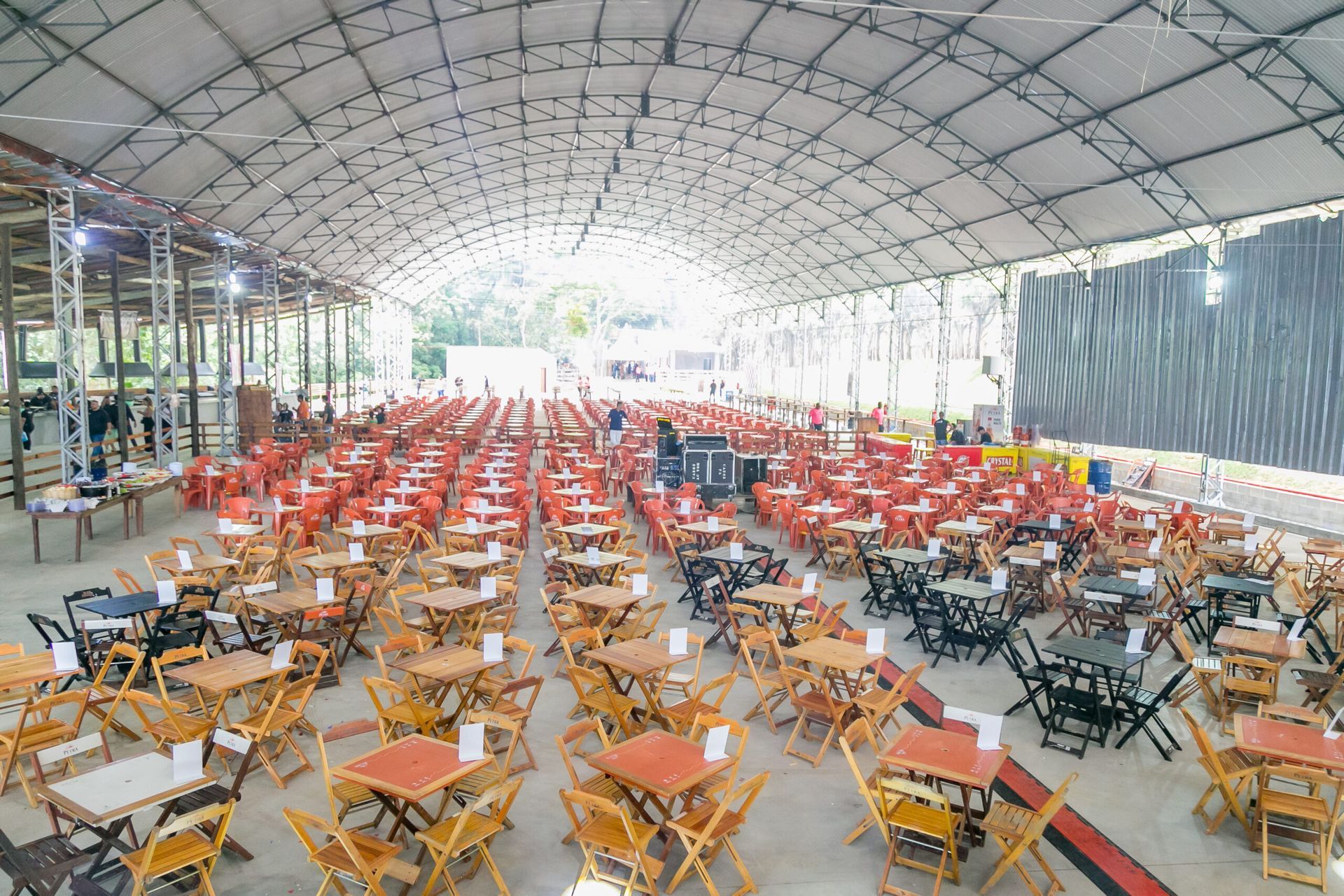 Uma grande sala cheia de mesas e cadeiras sob um teto.