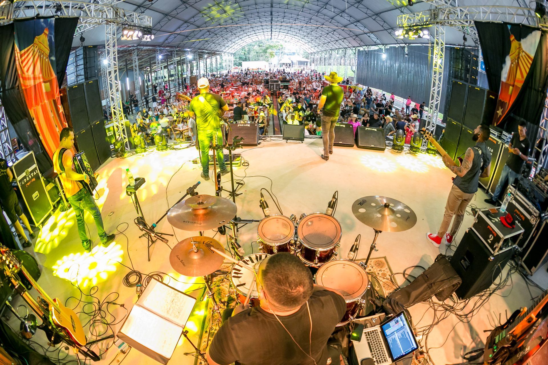 Um homem está tocando bateria em um palco na frente de uma multidão.