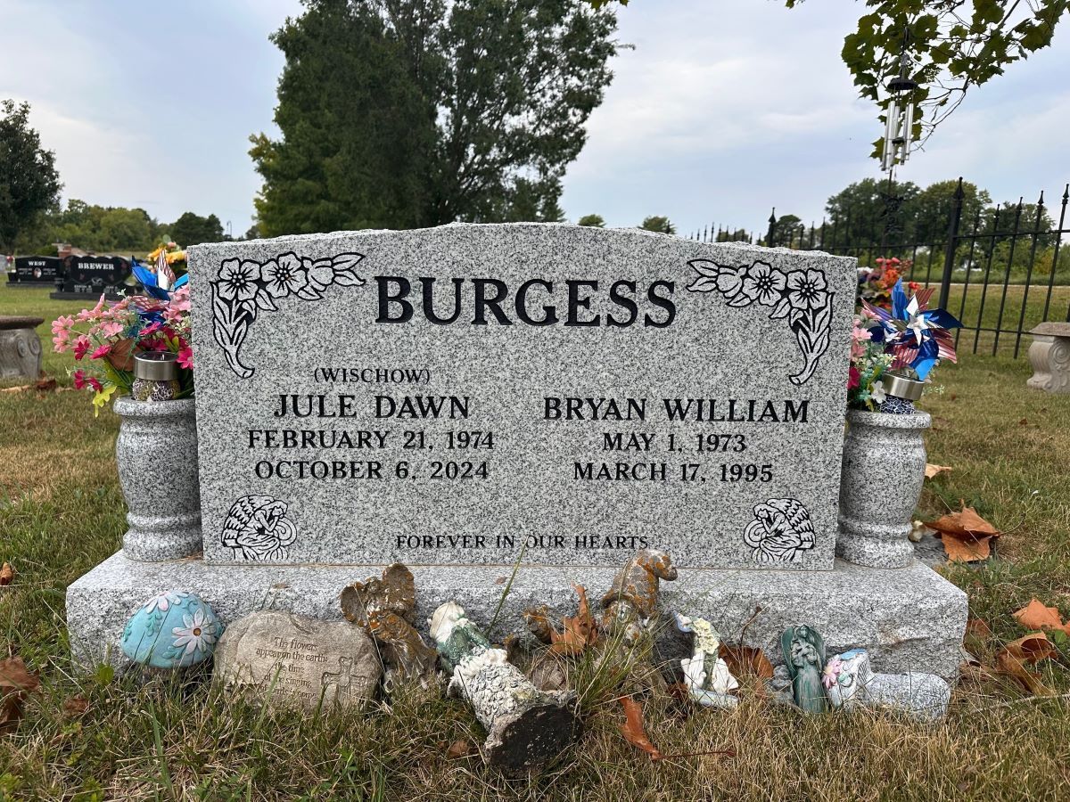 Gray Burgess headstone with names, dates, and floral arrangements at a cemetery.