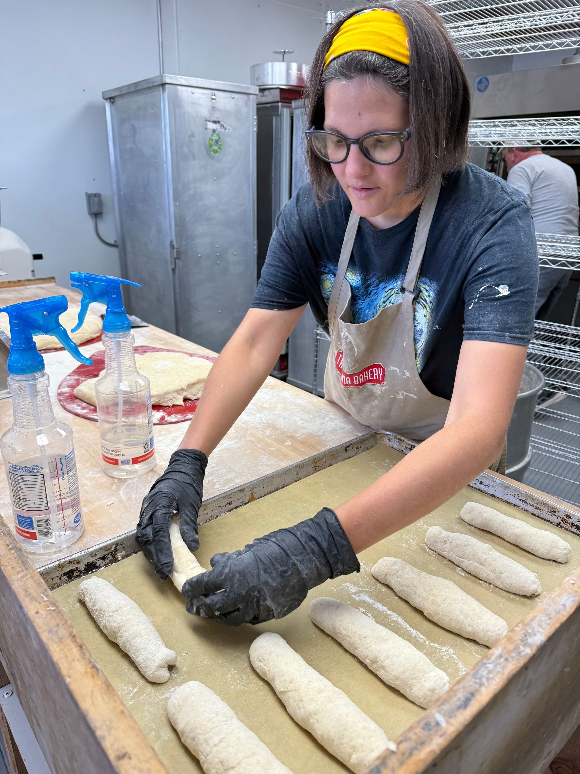 A woman is making bread in a bakery.
