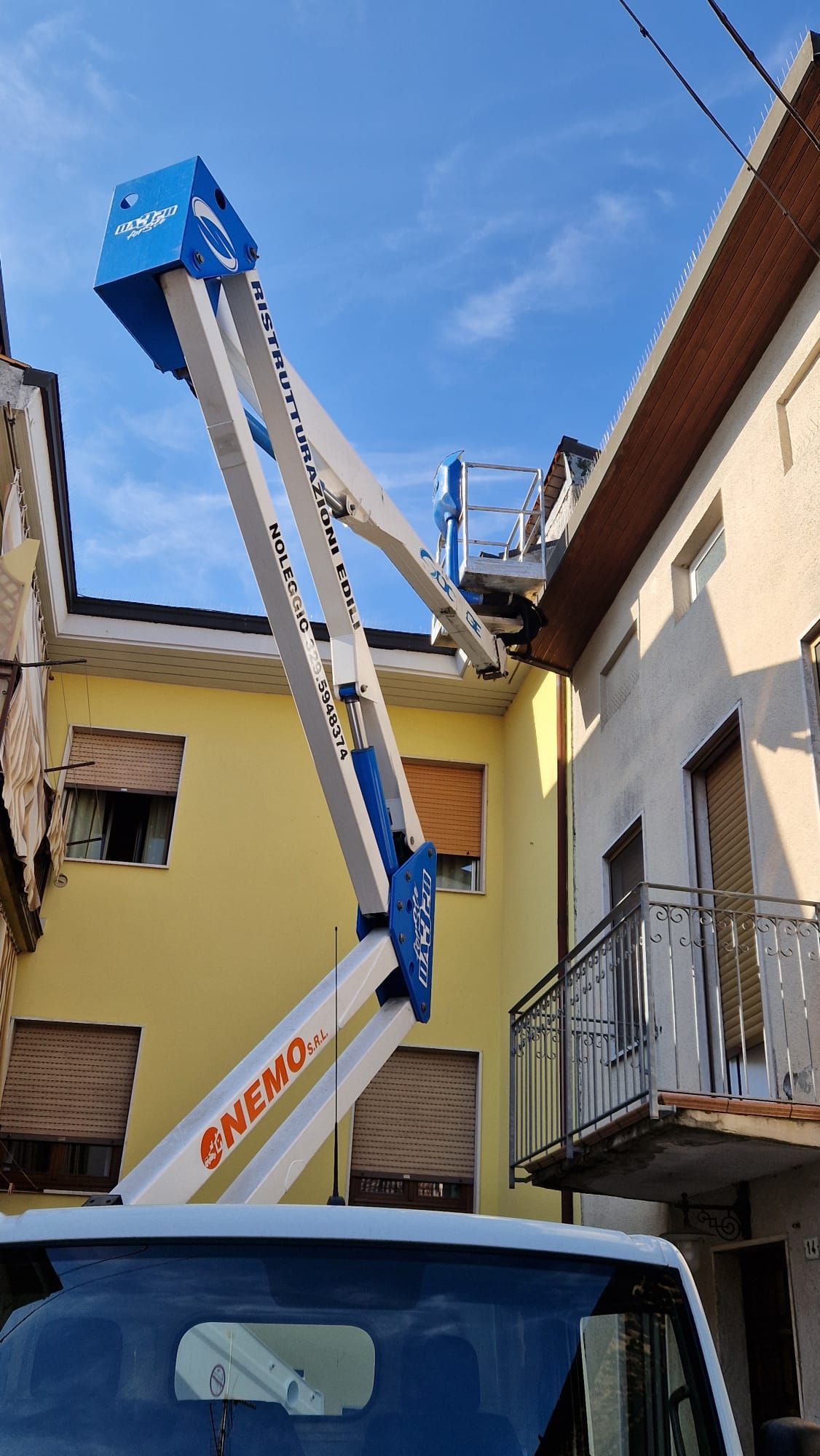 Ascensore aereo blu e bianco che si estende verso un edificio con uno sfondo di cielo azzurro.