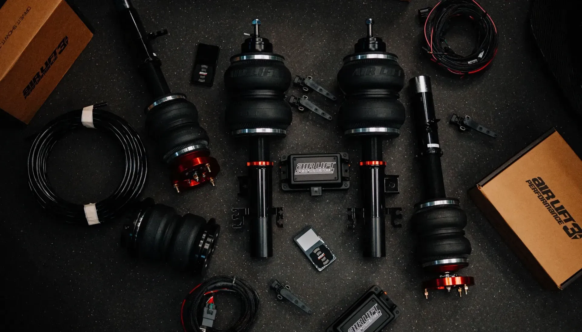 Air suspension kit laid out on a dark surface; includes shocks, air bags, and wiring.