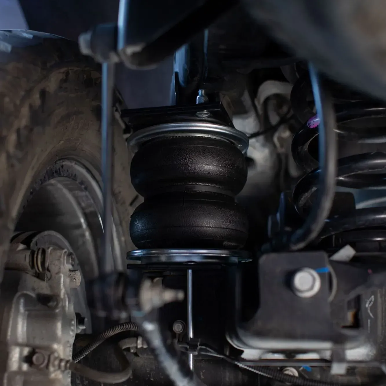 Black air spring suspension on a vehicle, close-up view.