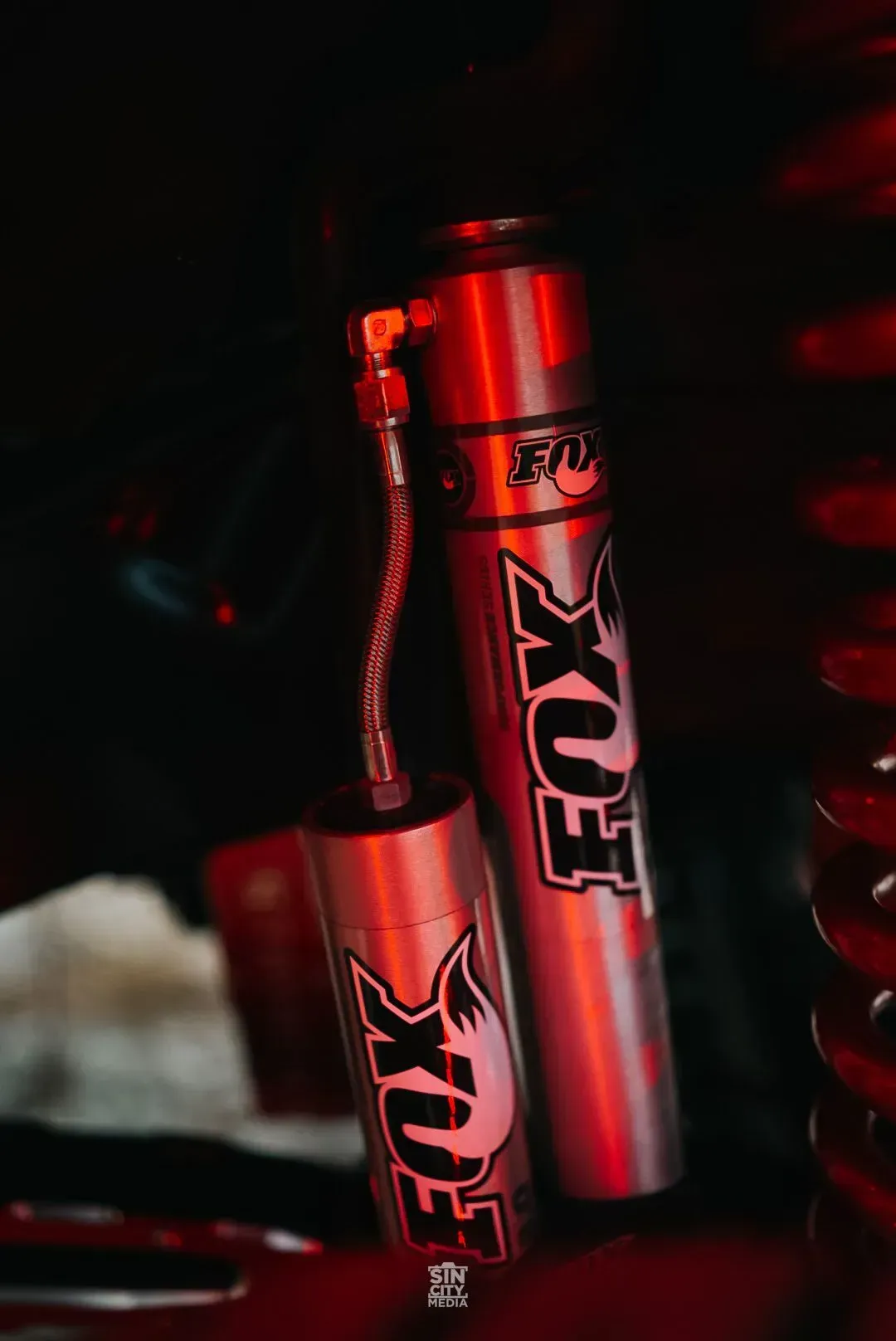 Fox shock absorber with a reservoir, in red lighting.
