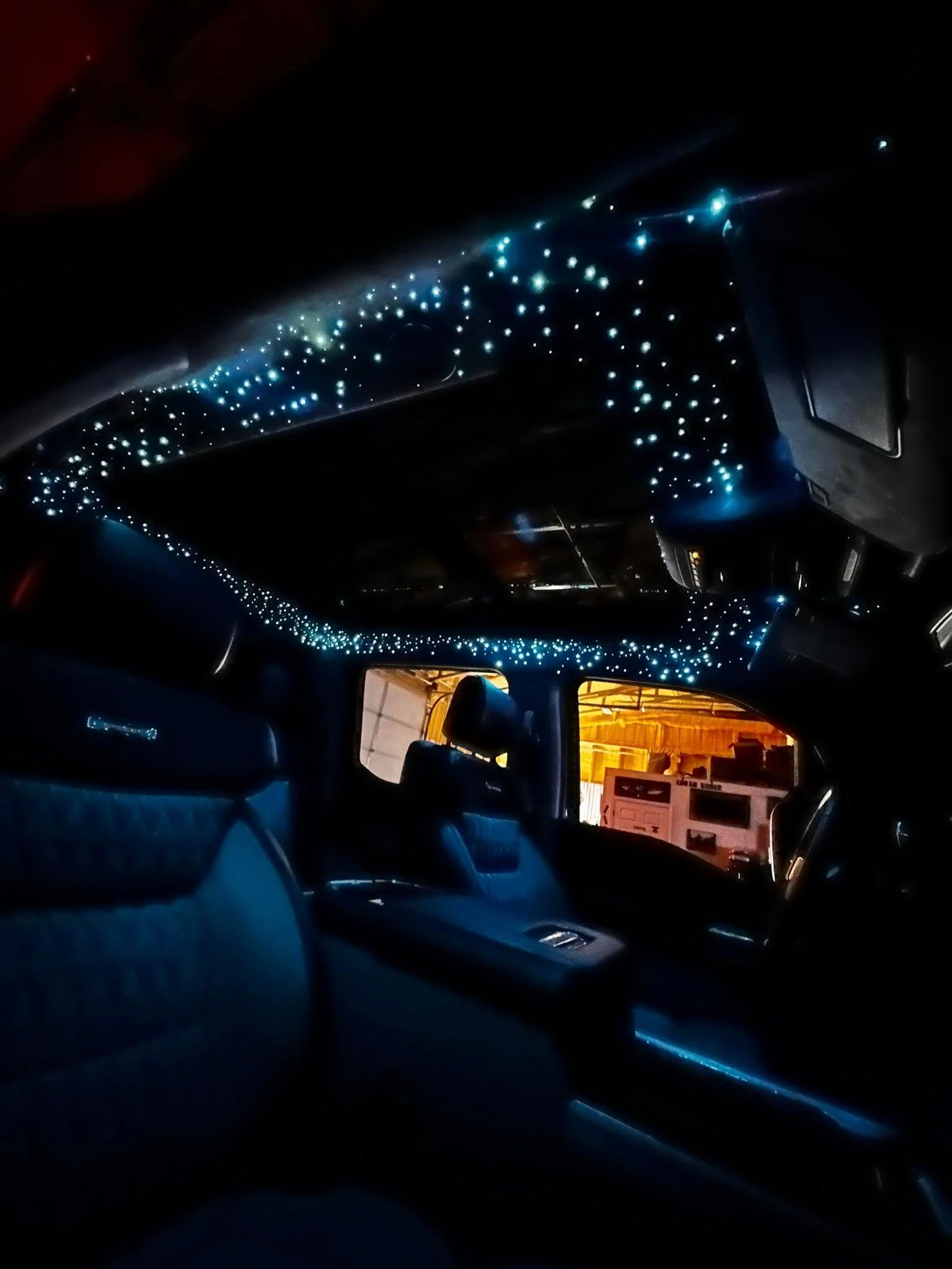 Interior car view with blue starry lights on the ceiling. Dark blue seats and dashboard.