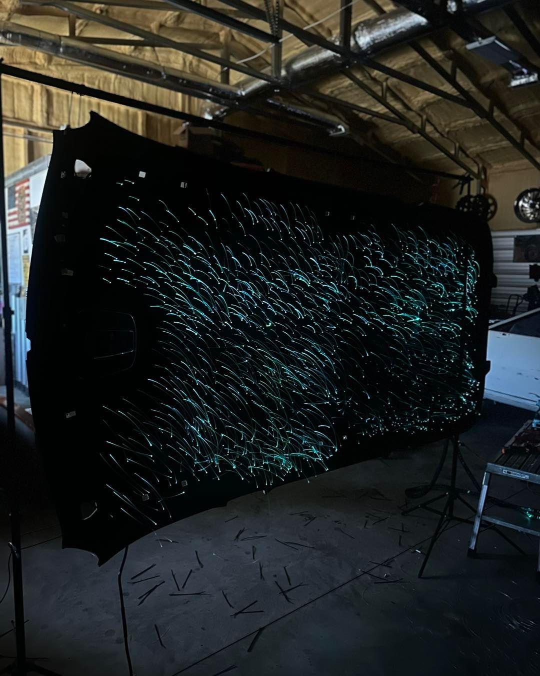 Dark fabric with glowing green streaks, possibly fiber optics, in an industrial setting.