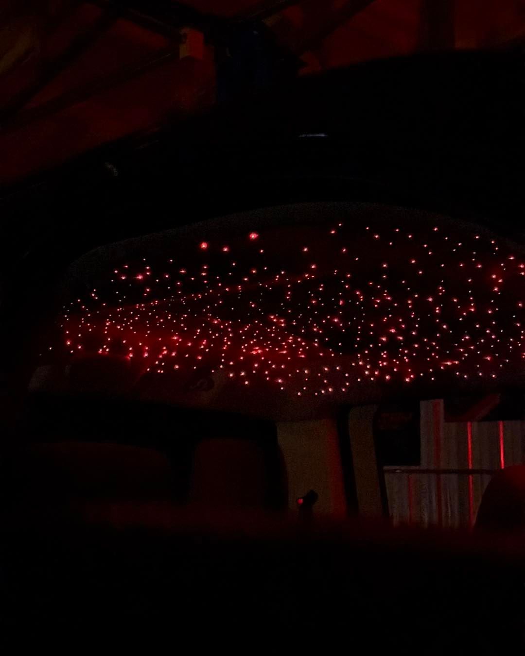 Red starlight ceiling inside a car; dim, ambient lighting.