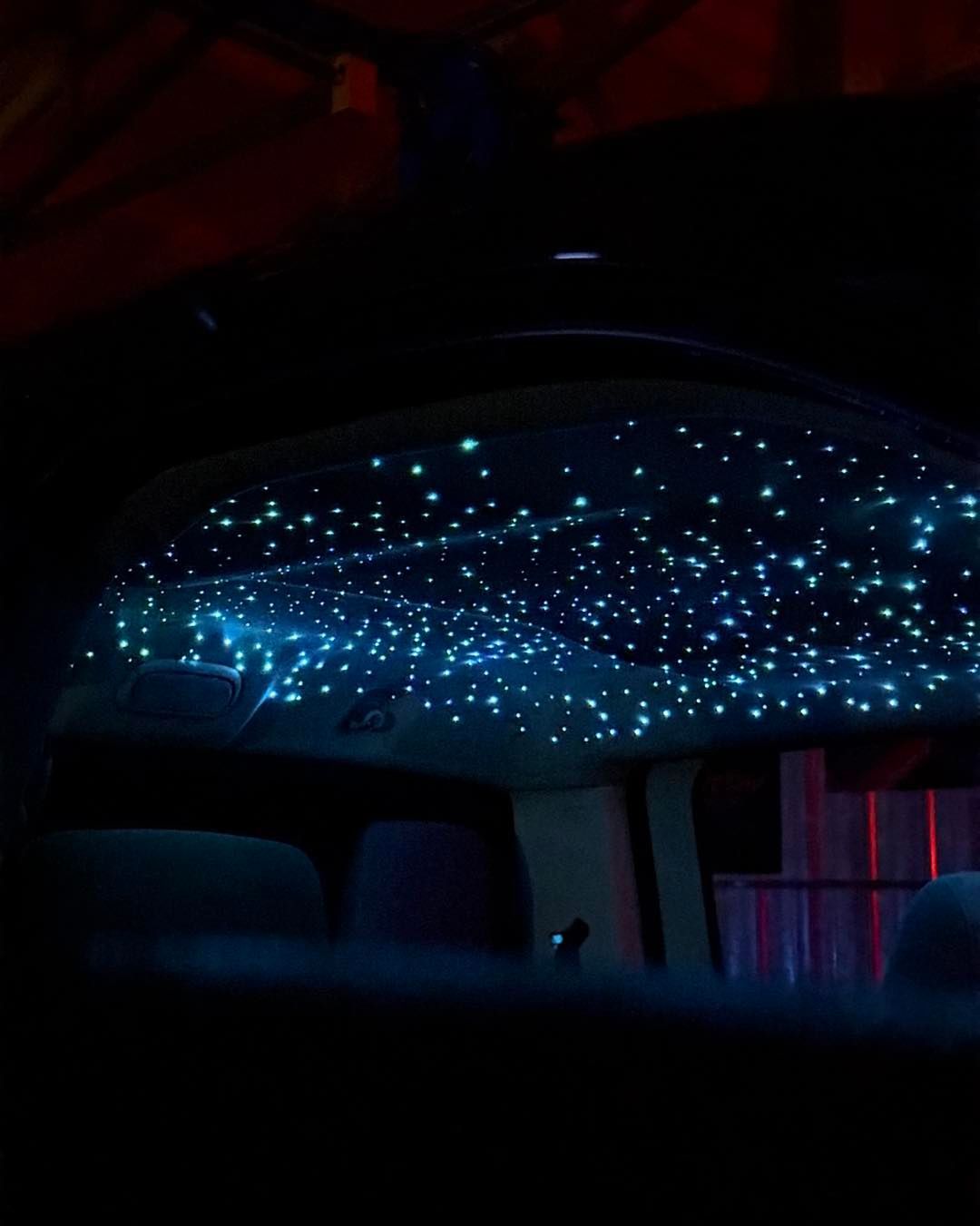 Car interior with starry night ceiling, blue and green lights.