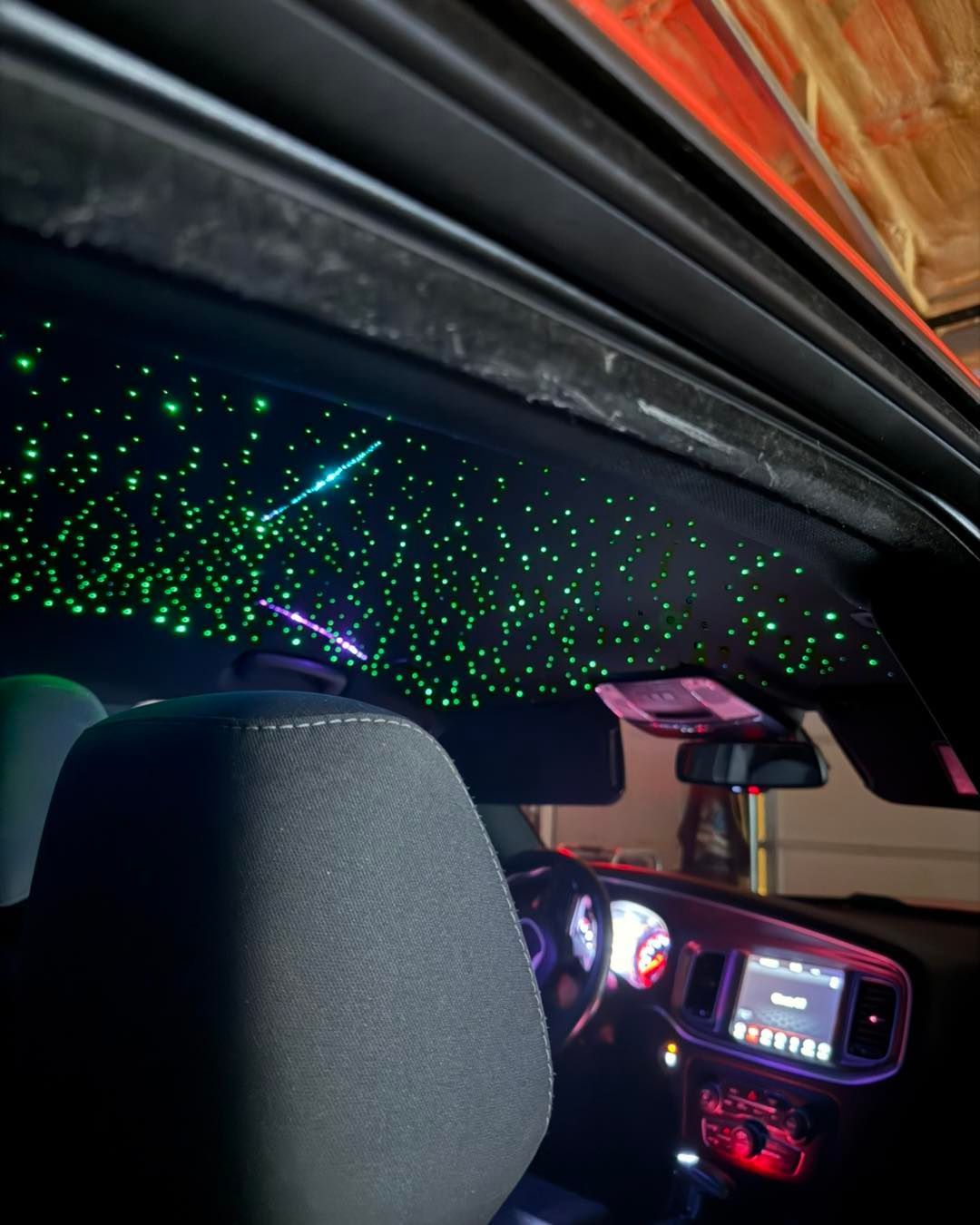 Interior car roof with green fiber optic stars, including a shooting star effect.