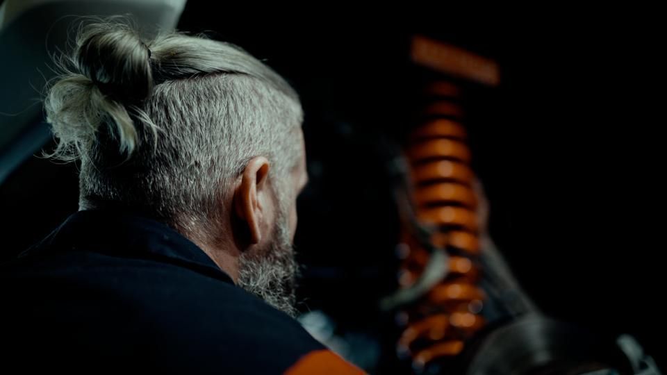 Black Ford F-150 truck with chrome rims on a lift inside a garage with an American flag on the wall.