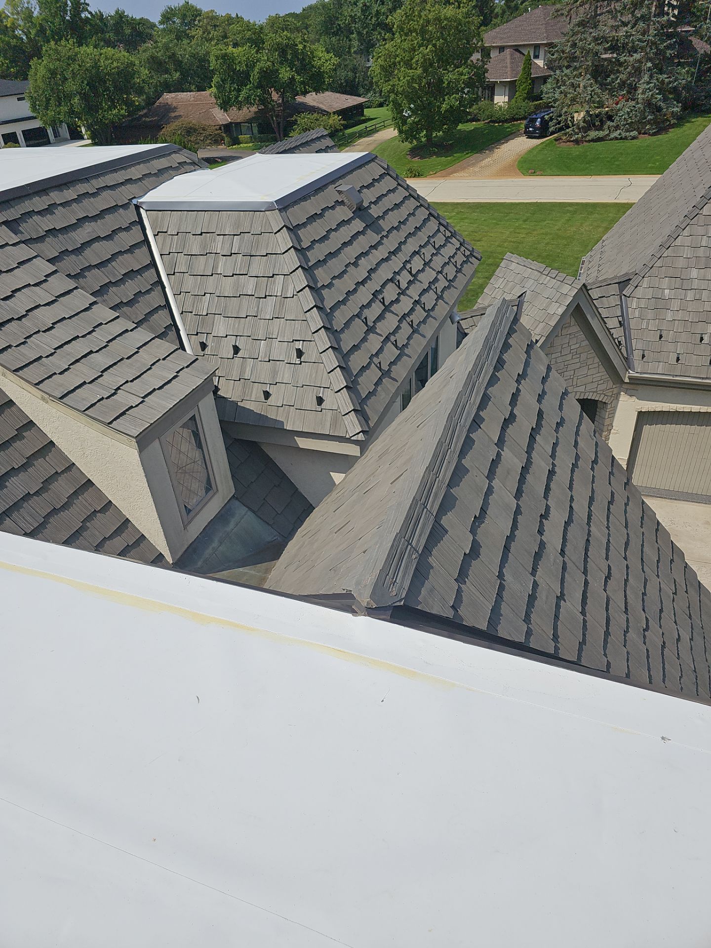 Aerial view of a blue metal roof under construction with three chimneys.