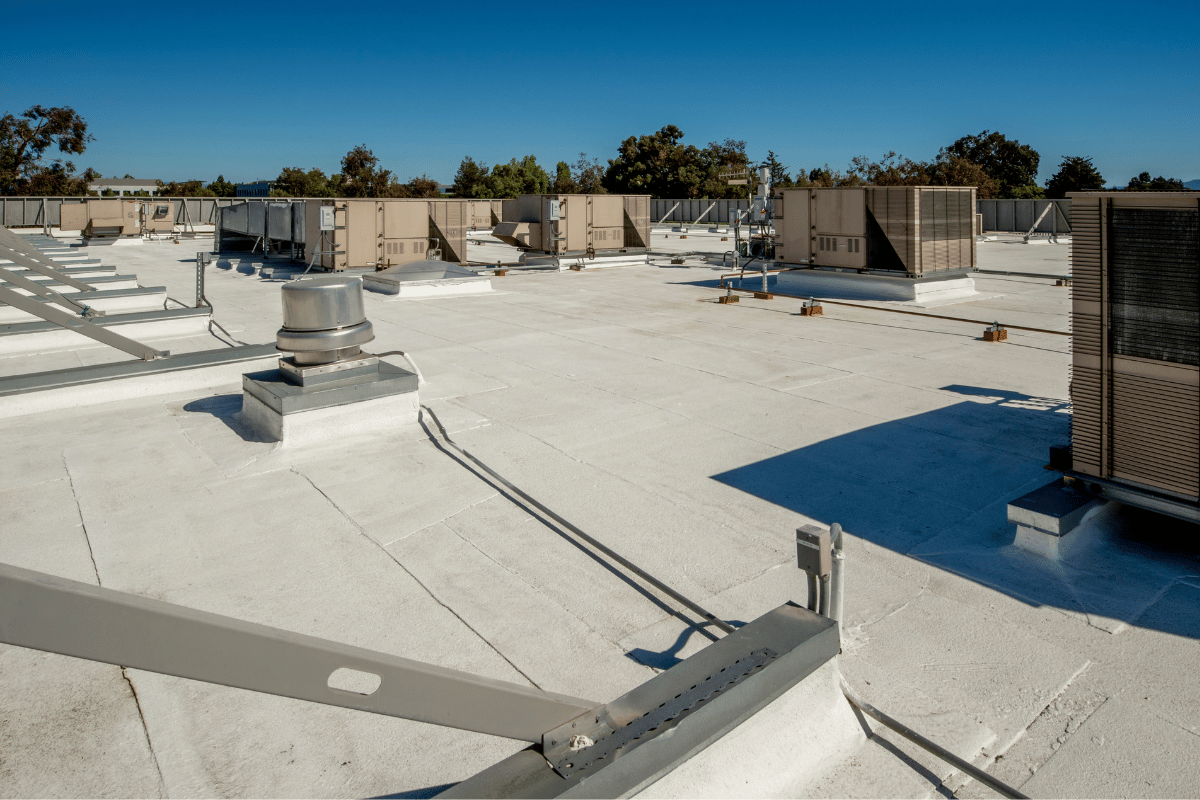 White commercial roof with HVAC units under a blue sky.