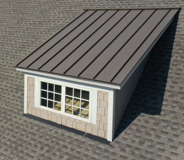 Dormer with a metal roof and a multi-pane window on a shingled roof.