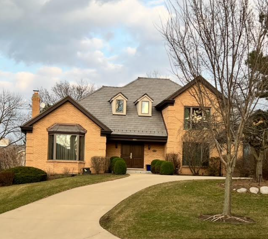 A section of a house with a downspout and siding, autumn leaves in the background.