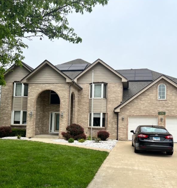 Brick wall with peeling paint, gray roof, trees, and blue sky.
