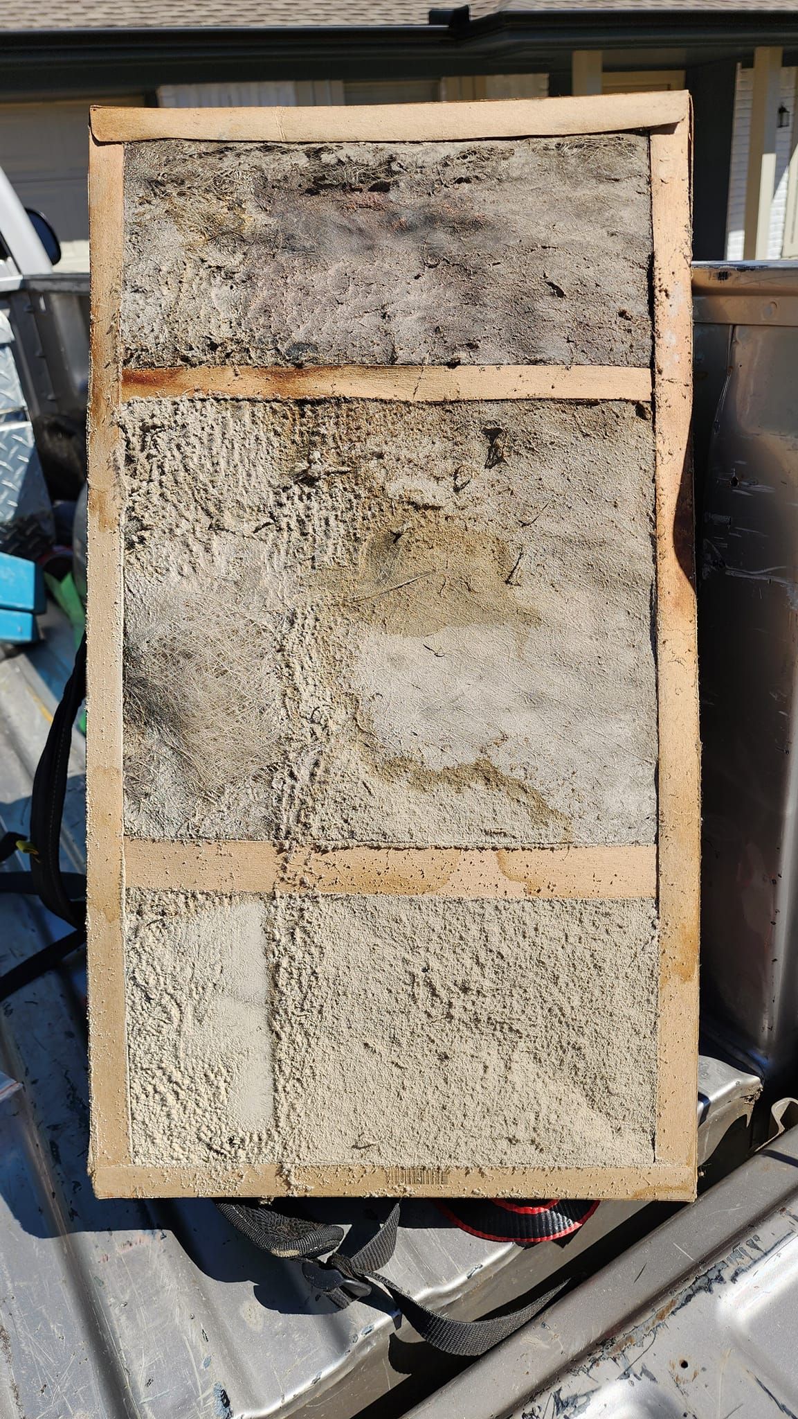 A piece of wood is sitting on top of a metal container.