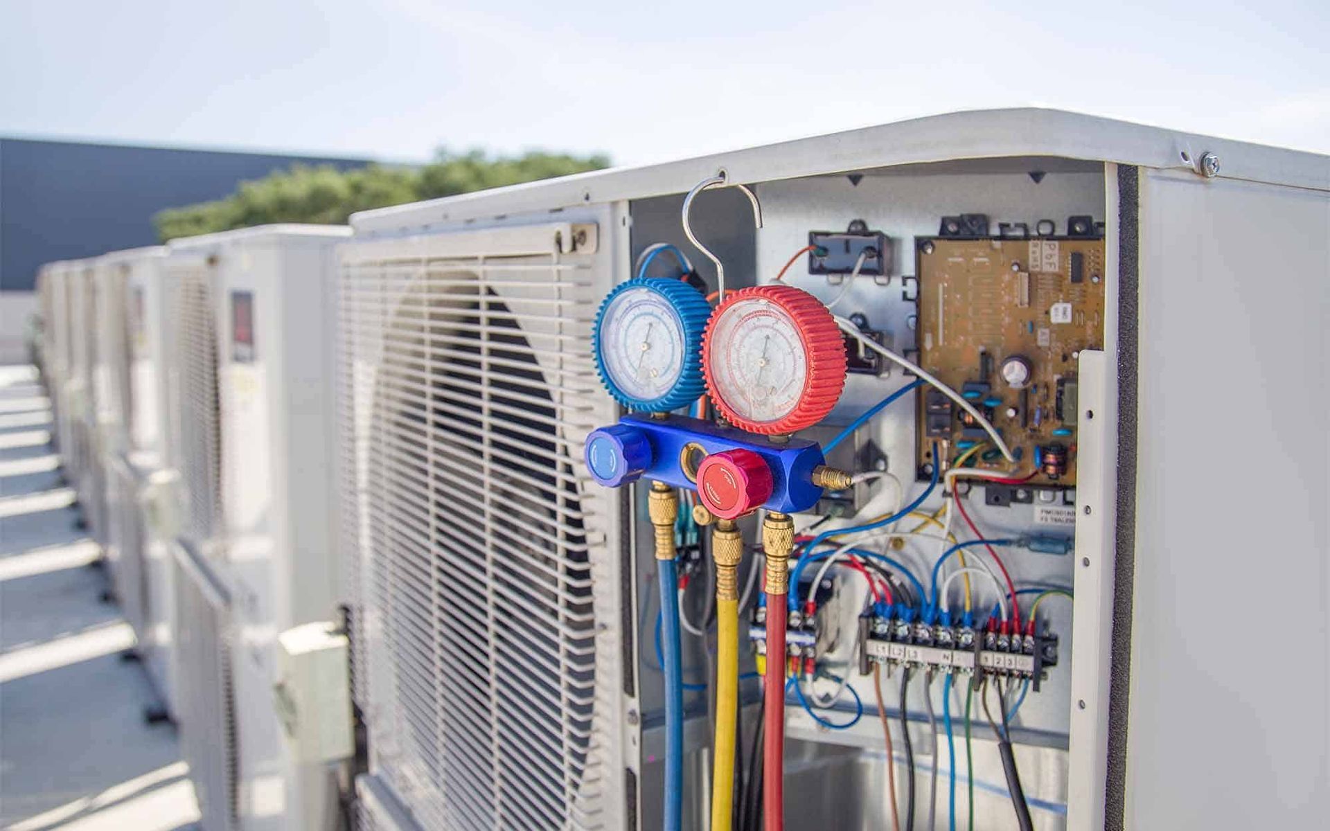 A row of air conditioners are sitting next to each other on a roof.