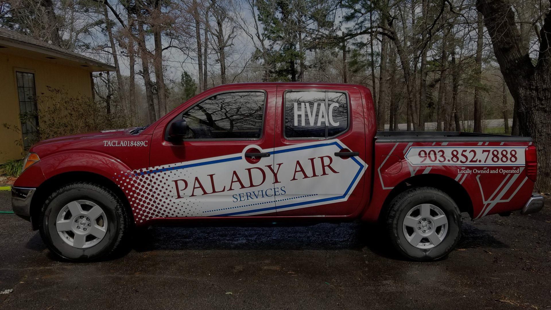 A red palady air truck is parked in front of a house