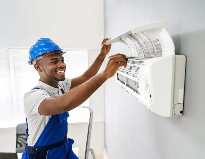 A man is fixing an air conditioner on a wall.