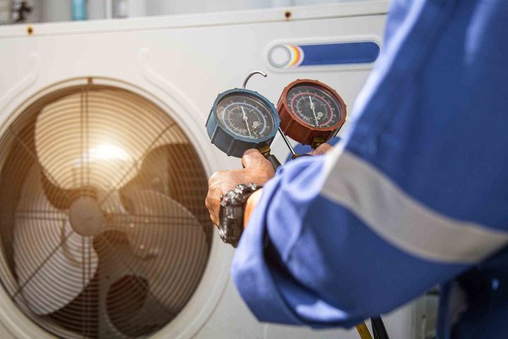 A man is holding two gauges in front of a fan.