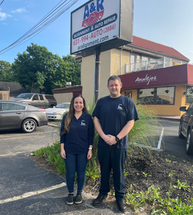 Two people, a woman and a man, in front of an auto repair shop sign, A&K,  on a sunny  | A & R Auto Repairday.