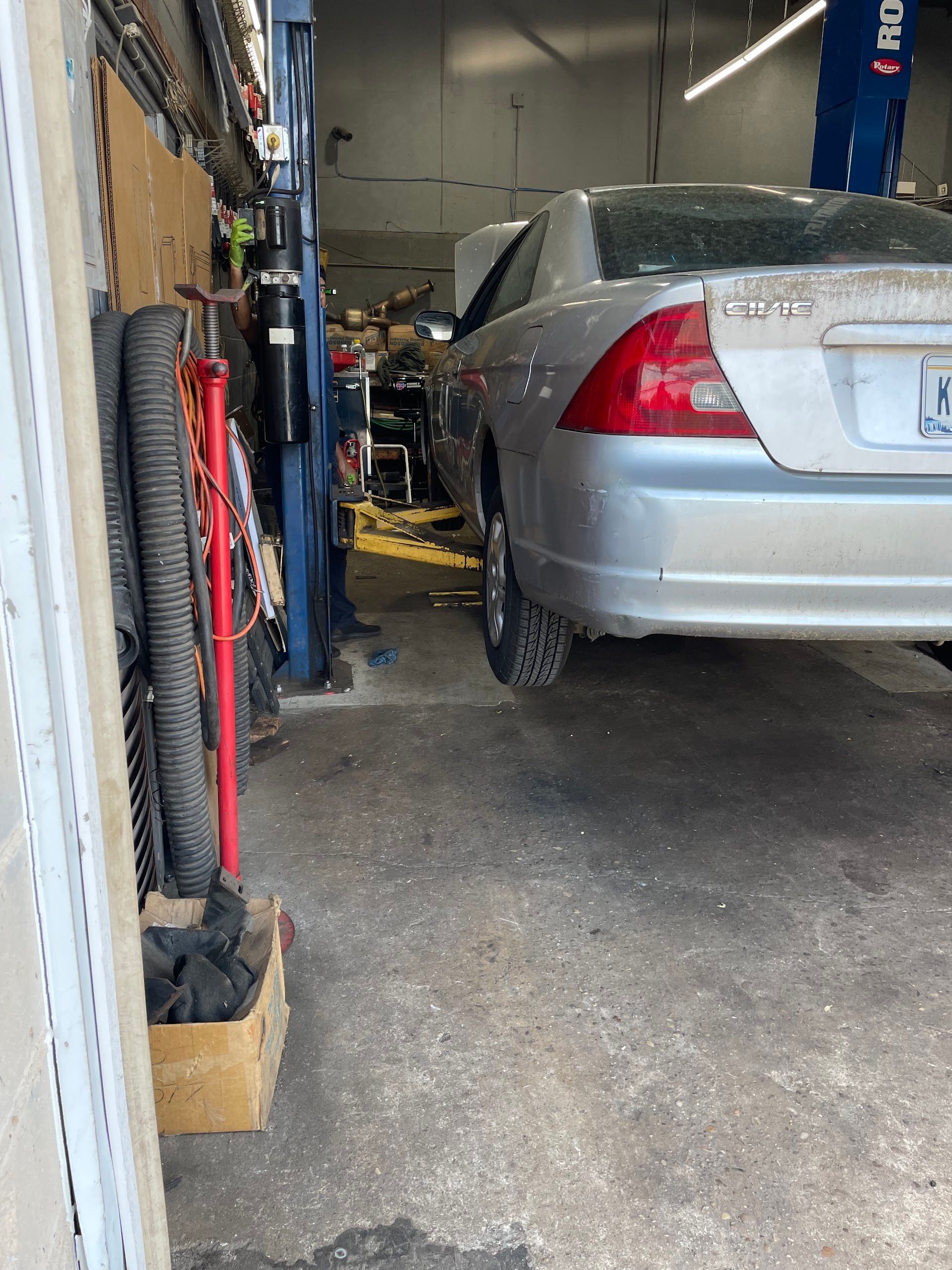 Silver car on a lift in a garage; tires and tools on the left. | A & R Auto Repair