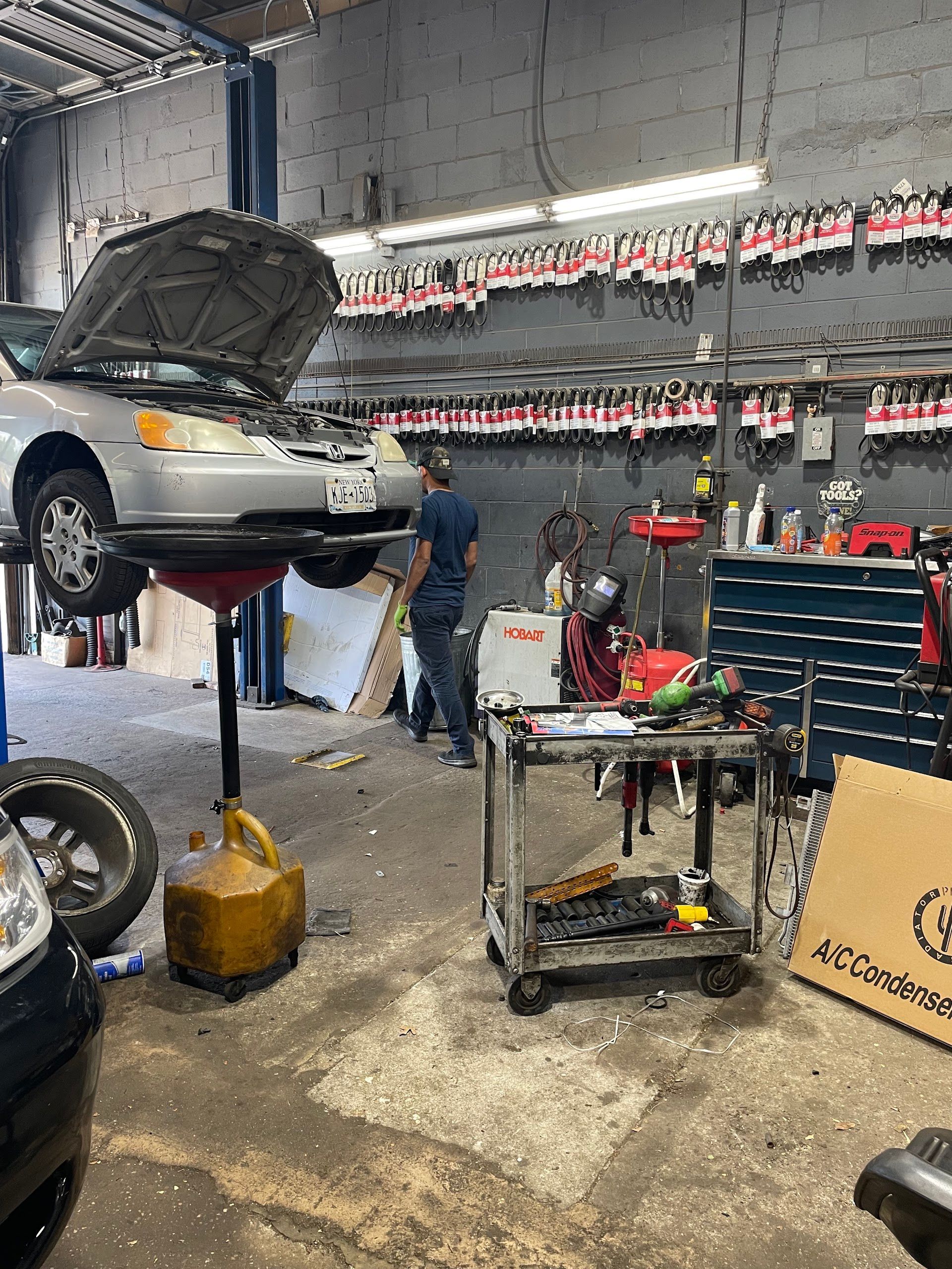 A mechanic working on a car raised on a lift in a garage. | A & R Auto Repair
