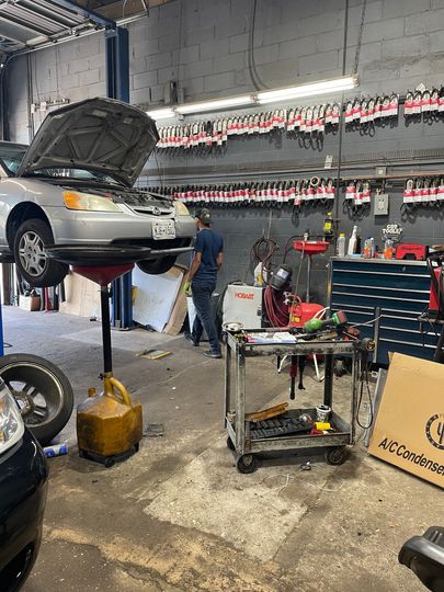 A mechanic working on a car raised on a lift in a garage. | A & R Auto Repair