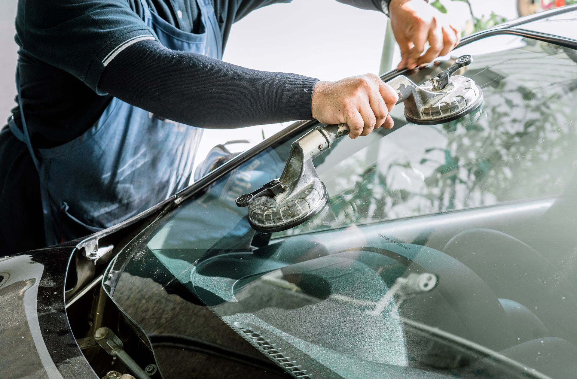 Un homme installe un pare-brise sur une voiture.