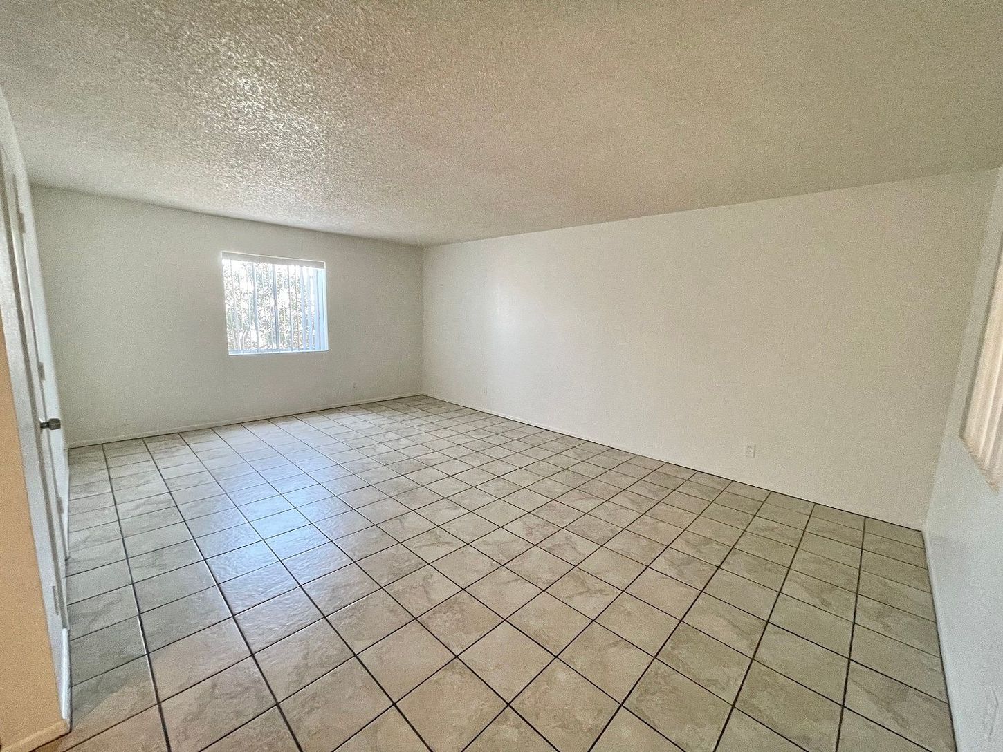 Empty room with tiled floor, white walls, and a small window.