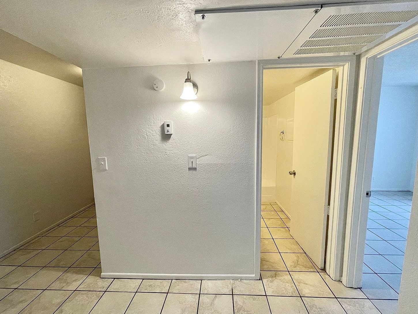 Hallway with white walls, tiled floor, and doors leading to other rooms.