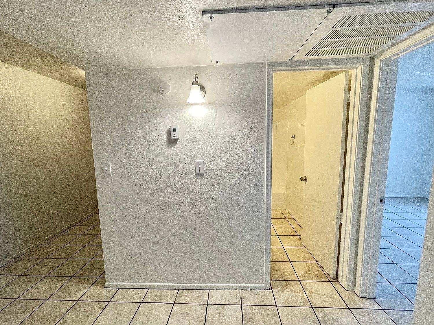 Hallway with white walls, tiled floor, and doors leading to other rooms.