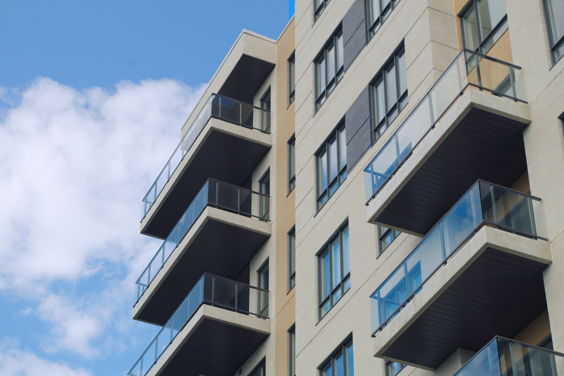 A tall building with many balconies against a blue sky