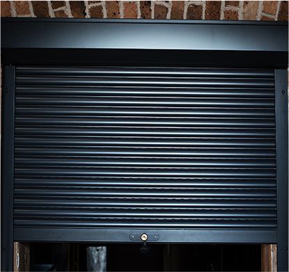 a close up of a black shutter on a brick wall .