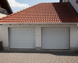 a white garage door with a red tile roof